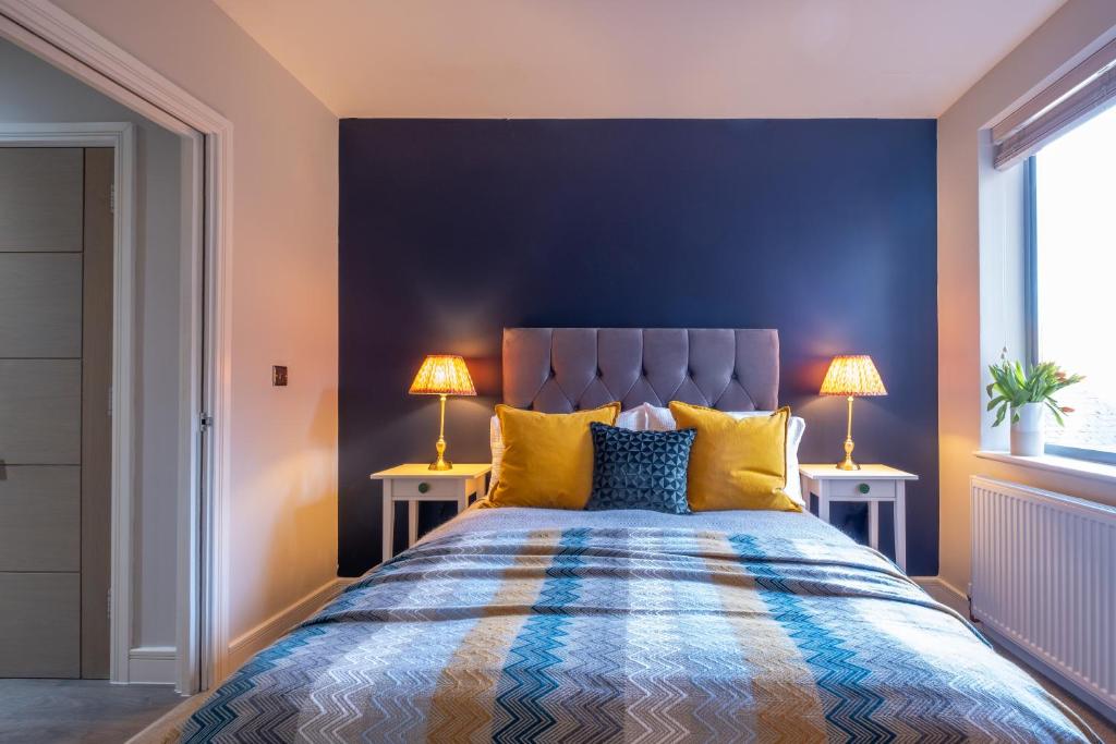 Un dormitorio con una pared azul y una cama con almohadas amarillas. en Church View, Geneva House, en Peterborough