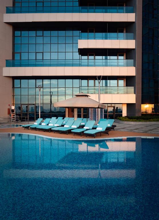 a pool with lounge chairs in front of a building at Millennium Place Barsha Heights Hotel in Dubai