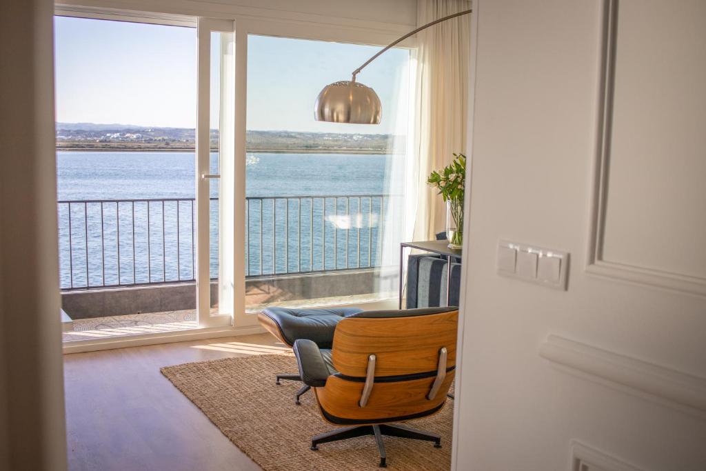 een kamer met een stoel en uitzicht op de oceaan bij Apartamento sobre el rio Guadiana in Ayamonte