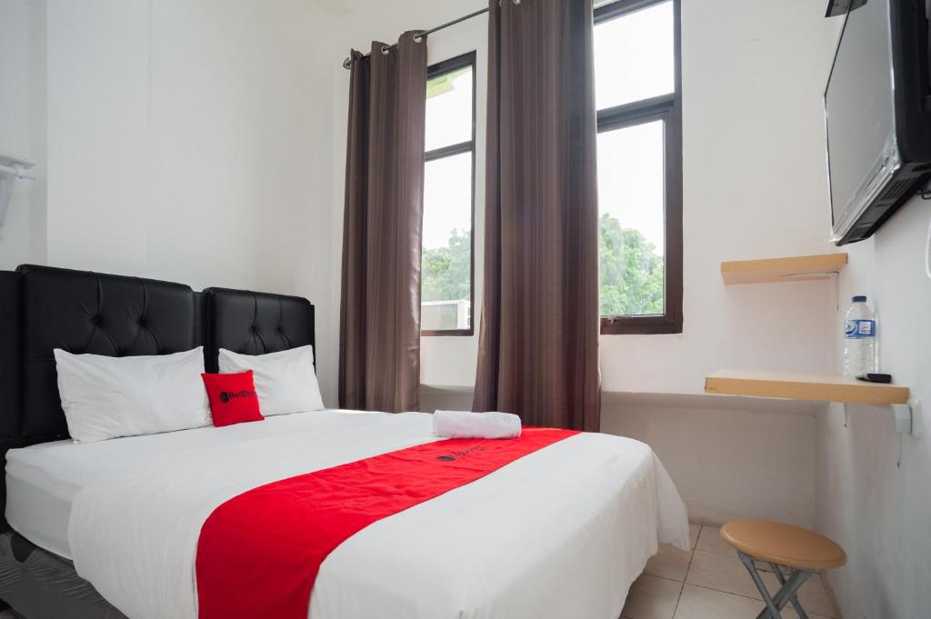 a bedroom with a large bed with a red blanket at RedDoorz at Jalan Bangau Palembang in Palembang