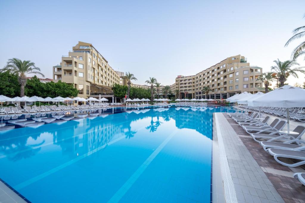 une grande piscine avec des chaises longues et des bâtiments dans l'établissement Selectum Family Resort Side, à Kizilagac