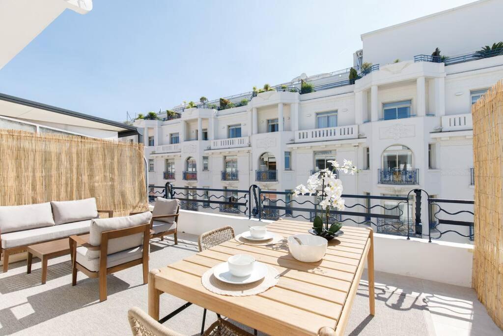 a patio with a wooden table and chairs on a balcony at Martinez area Superb 1 bed w XXL terrace in Cannes