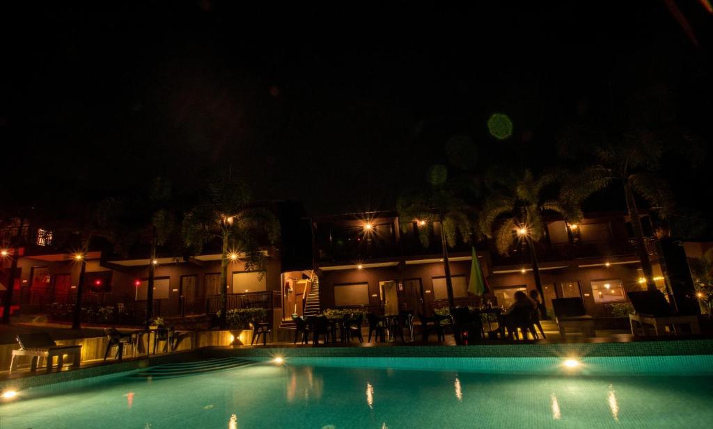 a swimming pool at night with tables and chairs at La Gracia Resort in Morjim