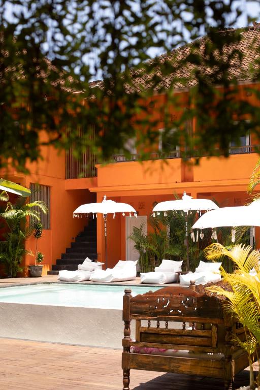 a bench sitting in front of a pool with umbrellas at The Room Padang-Padang in Uluwatu