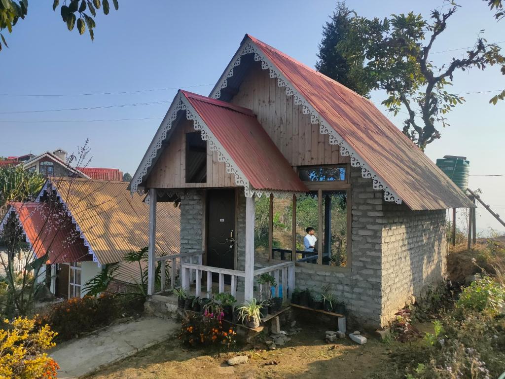 een klein huis met een rood dak bij Snow White Holiday Inn Homestay in Kalimpong
