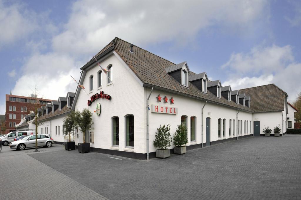 un grand bâtiment blanc avec un hôtel dans un parking dans l'établissement De Witte Hoeve, à Venray