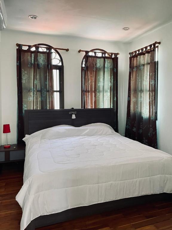 a bedroom with a large bed and two windows at 103/24 Kathu Waterfall in Phuket