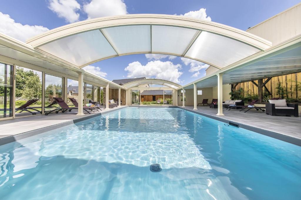 an indoor swimming pool with an arched ceiling at Les gîtes du Haut Pin in Calorguen