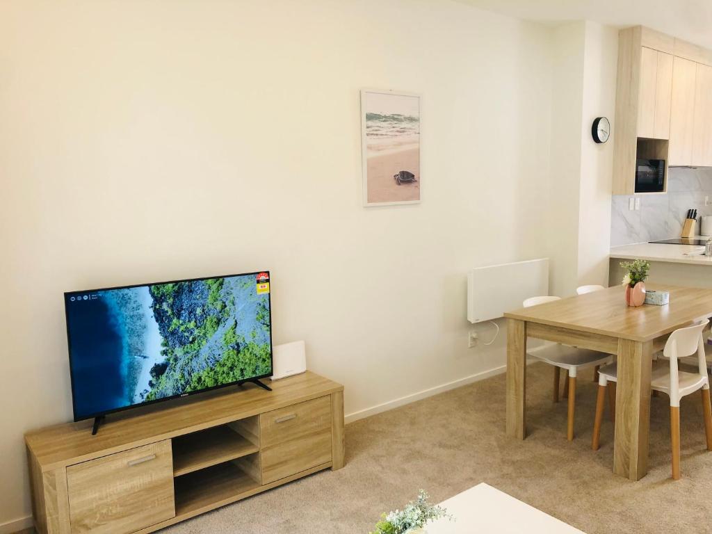 een woonkamer met een televisie en een tafel bij Cozy Brand New Townhouse 26 in Auckland