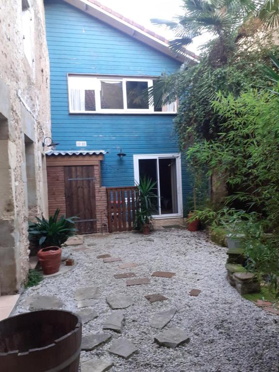 a blue house with a stone path in front of it at Duplex à Samadet in Samadet