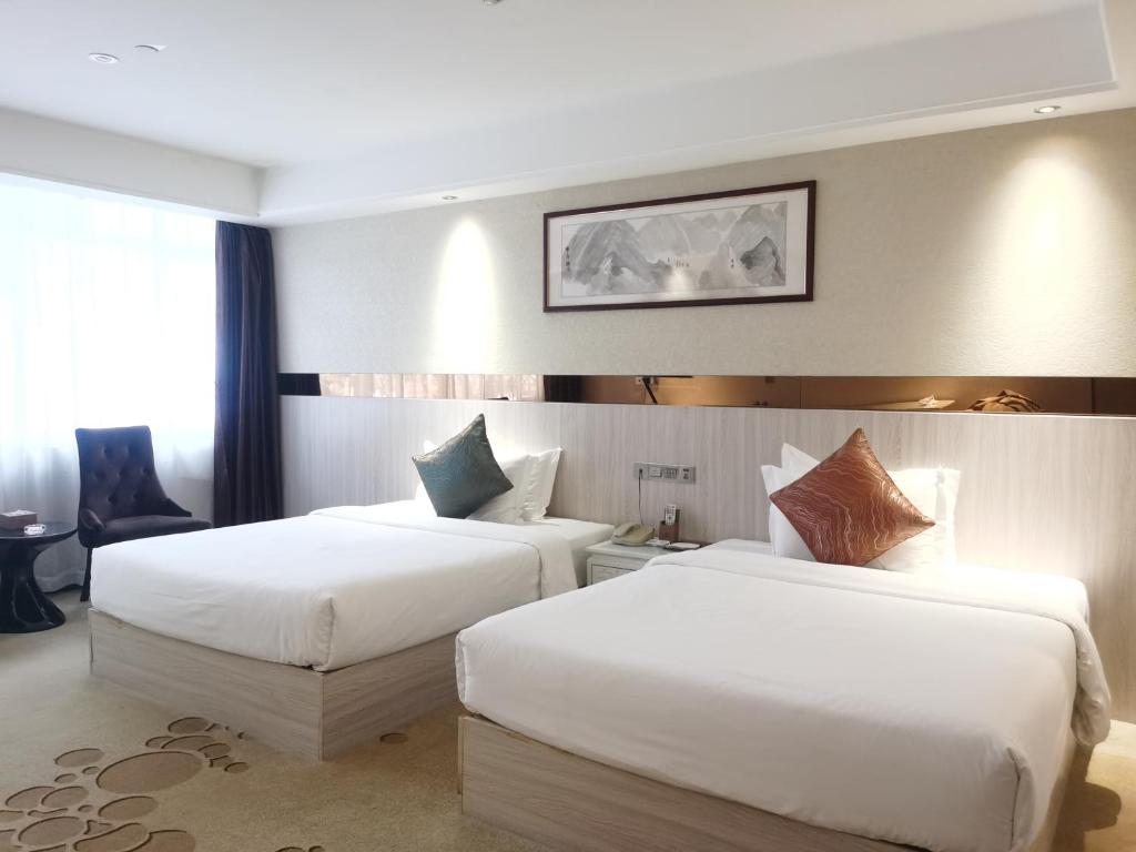 duas camas num quarto de hotel com lençóis brancos em Paco Hotel Tianhe Coach Terminal Metro Guangzhou em Guangzhou