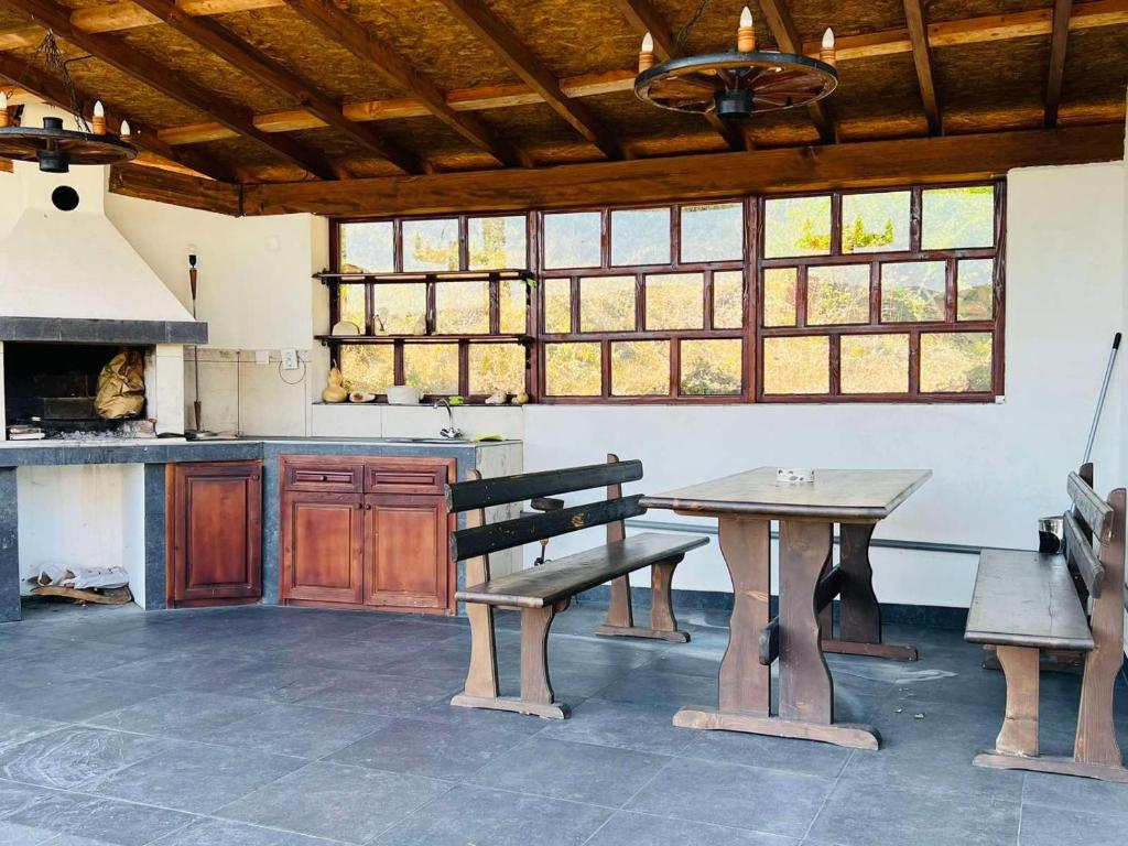 une cuisine avec un banc, une table et des fenêtres dans l'établissement Къща за гости Под Манастира, à Skrino