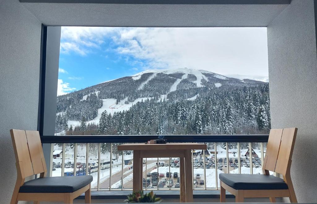 - une vue sur la montagne depuis une fenêtre avec une table et des chaises dans l'établissement Luxury Apartment Zimska idila, à Bjelašnica
