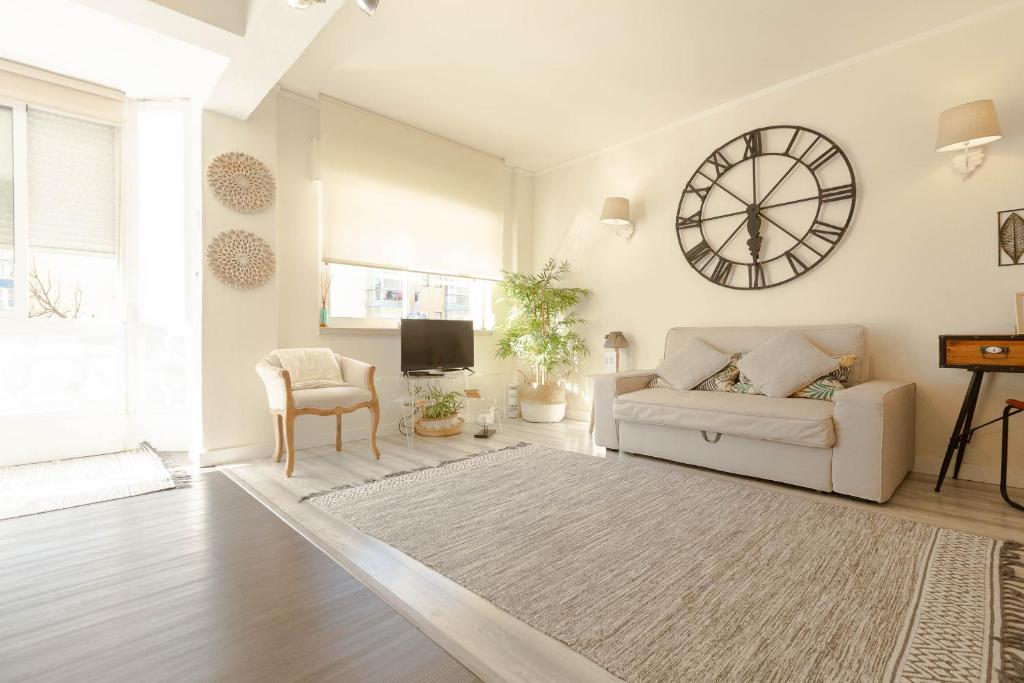 a living room with a couch and a clock on the wall at Beachome4u in Carcavelos