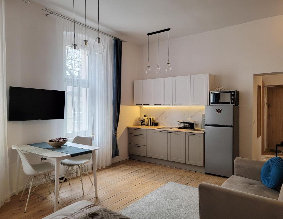 a small kitchen with a table and a refrigerator at Apartament Za Murami Gliwice in Gliwice