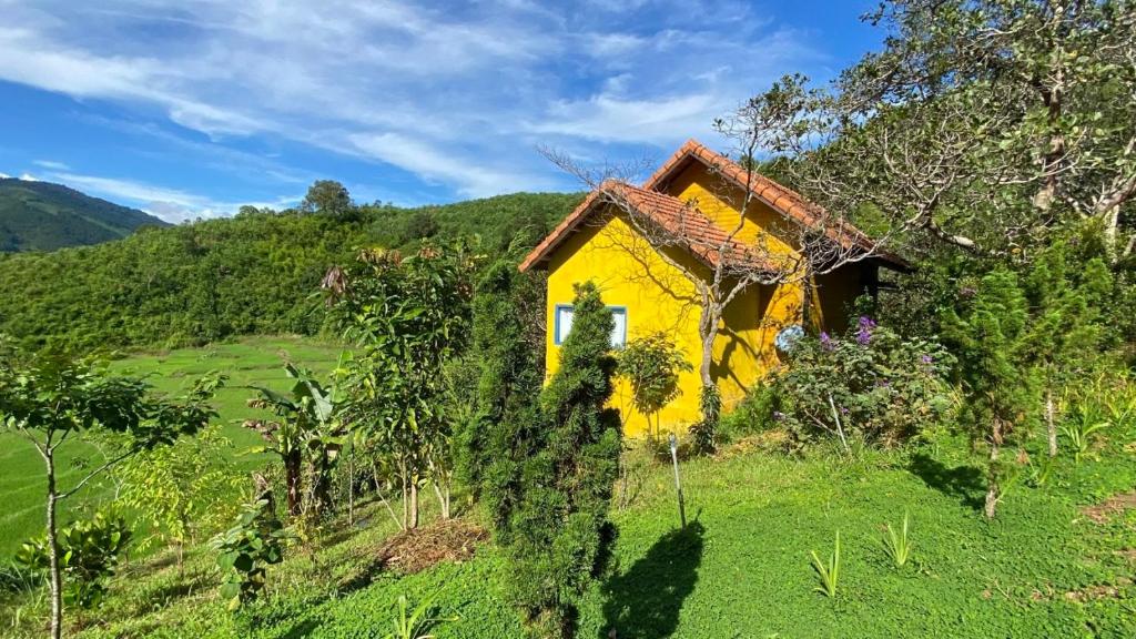 una casa amarilla al lado de una colina en Zen Cafe Countryside Retreat 