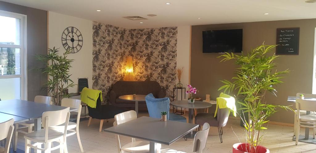 ein Restaurant mit Tischen und Stühlen und einem TV an der Wand in der Unterkunft Campanile Hotel Chantilly in Chantilly