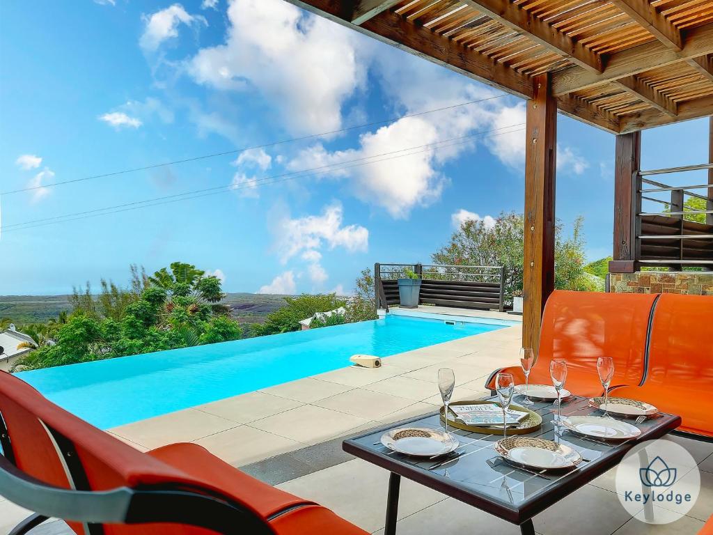 a patio with a table and chairs and a pool at Les Balcons du sud - Villa Perle de l'Océan - 180 m2 avec piscine - Les Avirons in Les Avirons