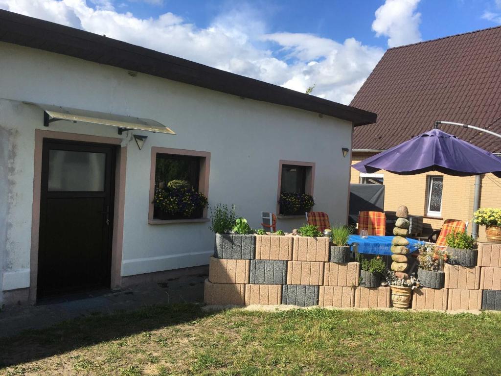 ein Haus mit einem Tisch und einem Sonnenschirm im Hof in der Unterkunft Bungalow in Mesekenhagen