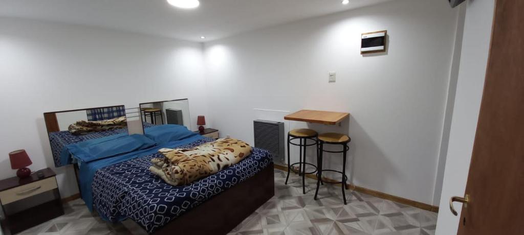 1 dormitorio con 1 cama, mesa y taburete en Alojamiento Los hermanos en Ushuaia