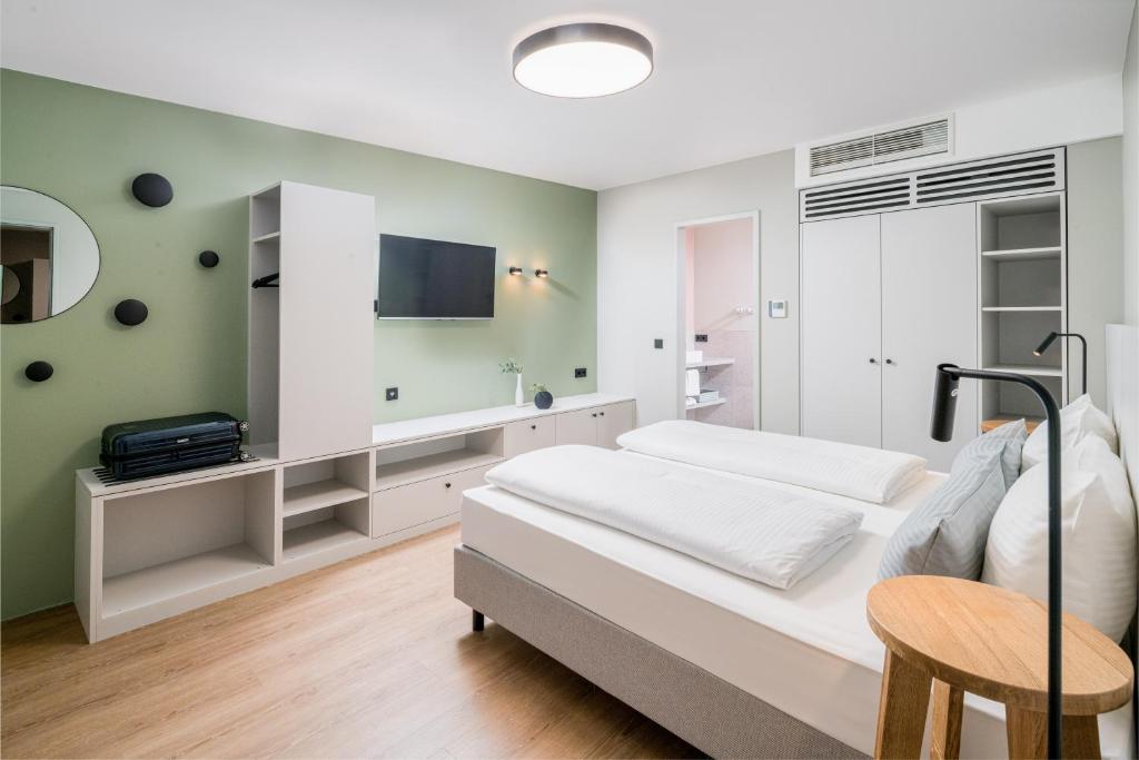 a bedroom with a bed and a tv on the wall at KOOS Hotel&Apartments - City Aparthotel in Munich