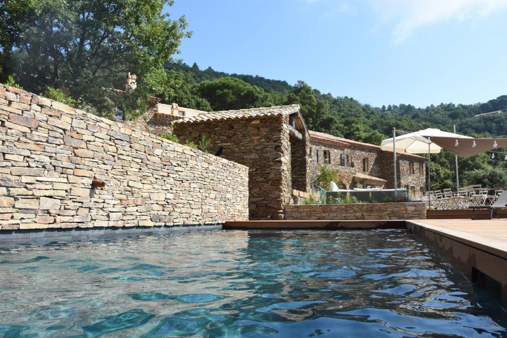 a swimming pool in front of a stone wall at Chambres d'hôtes Le Pontillaou in La Garde-Freinet