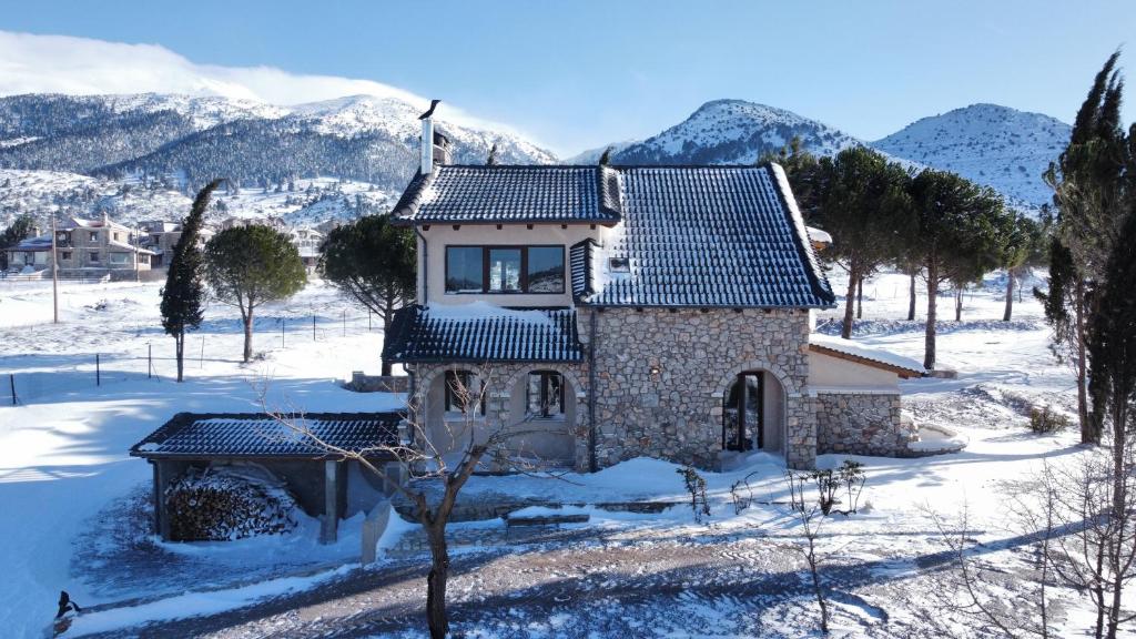 a house covered in snow with mountains in the background at Villa Dianne - Your Home in Mount Parnassos in Arachova