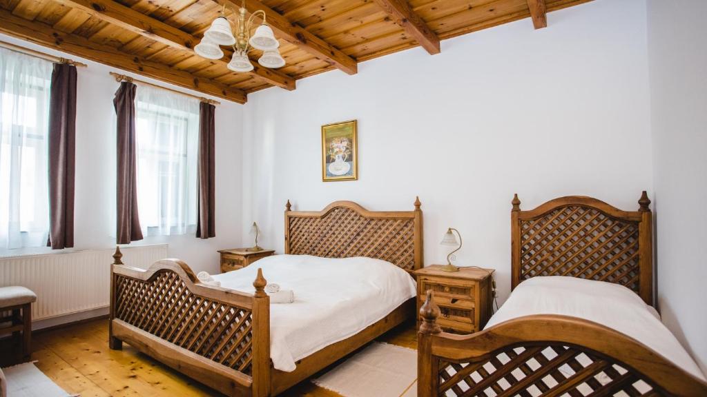 two beds in a bedroom with wooden ceilings and windows at Ginti Panzió, Őrség in Magyarszombatfa