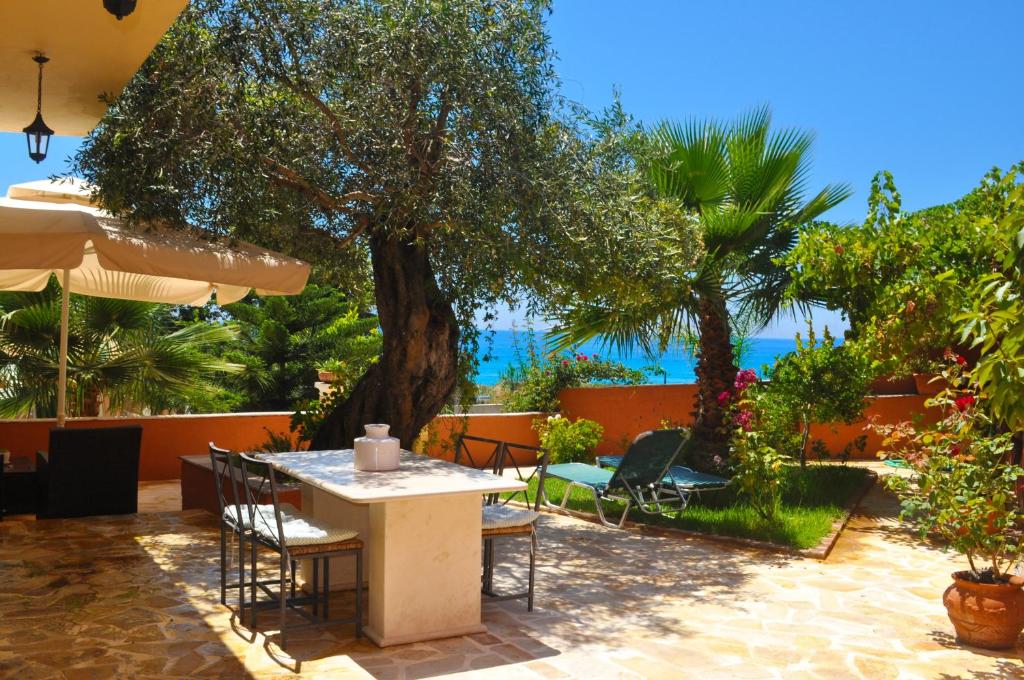 um pátio com uma mesa, cadeiras e uma árvore em House Angelos D with sea view and private garden - Agios Gordios Beach em Agios Gordios