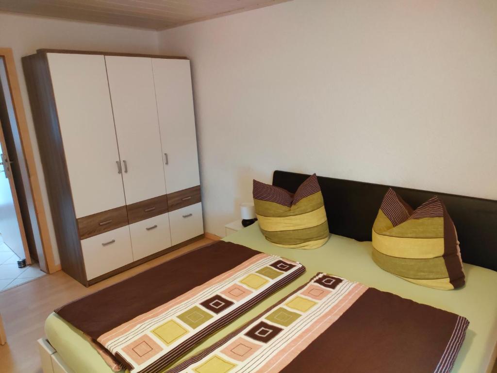 1 dormitorio con 1 cama con almohadas y armario en Susis Ferienwohnung, en Lahnau