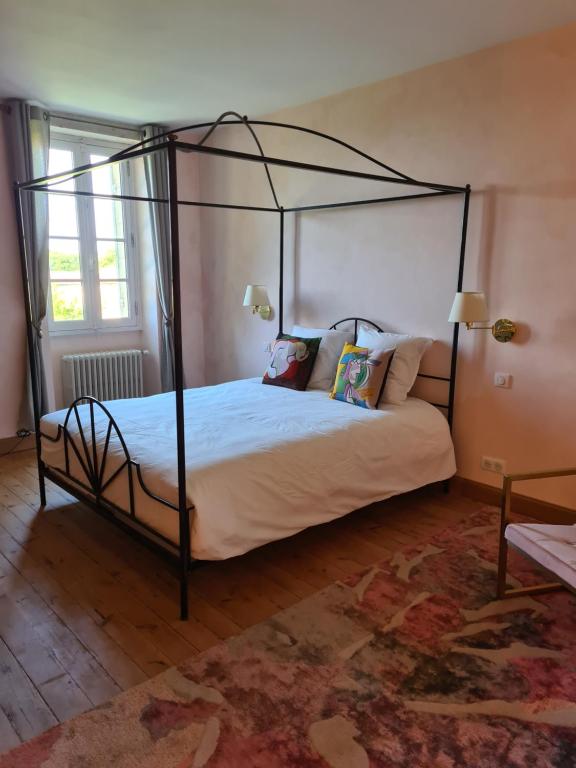 a bedroom with a black canopy bed with pillows at Jardin Meurin in Tabanac