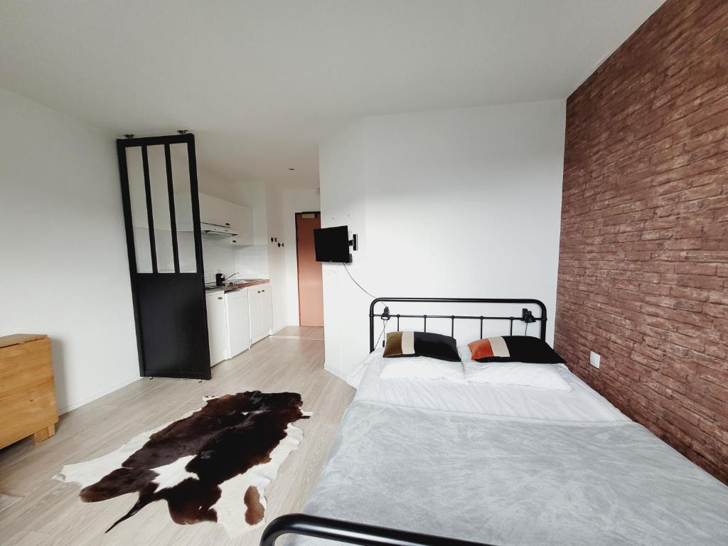a bedroom with a bed and a brick wall at Esprit industriel au pied du Futuroscope in Chasseneuil-du-Poitou