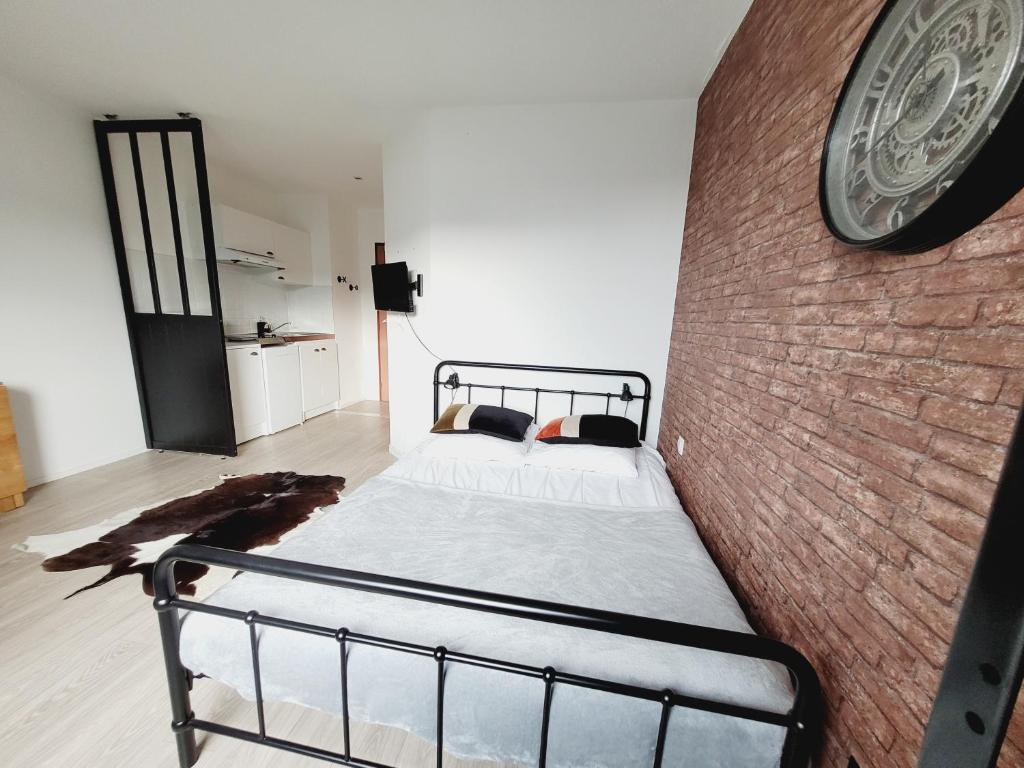 a bedroom with a bed against a brick wall at Esprit industriel au pied du Futuroscope in Chasseneuil-du-Poitou