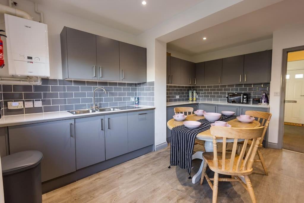 a kitchen with a table and chairs and a sink at 7 Bed House Pitchford Road in Earlham