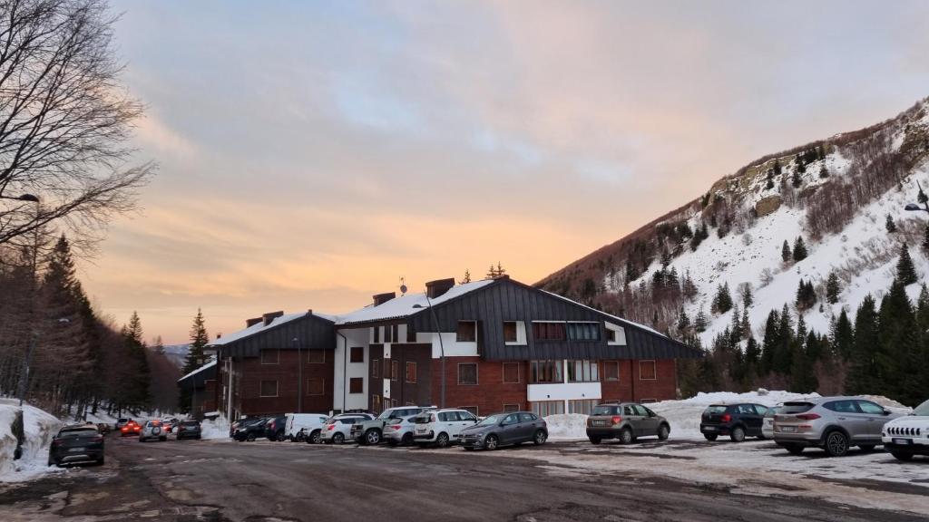 a large building with cars parked in a parking lot at Appartamento Val di Luce Relax Cristallo in Abetone