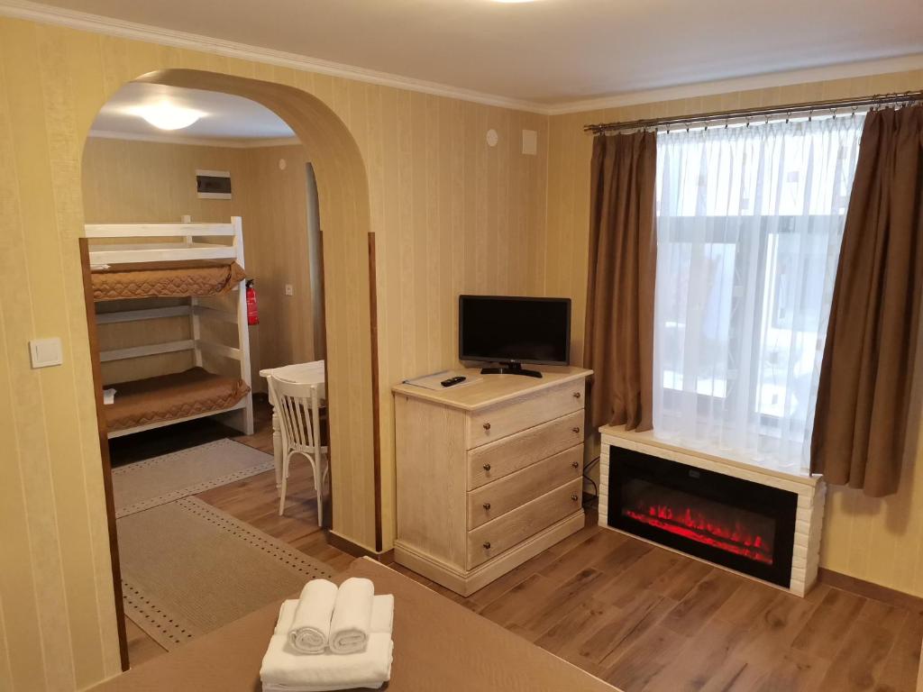 a living room with a fireplace and a bedroom with a bed at Самостоятелна Вила в Хаджи Марковата къща за гости в Дряново in Dryanovo