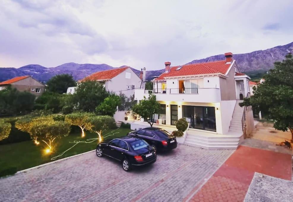a house with two cars parked in the driveway at Villa Lemon Garden - Apartment in Dubrovnik in Mlini