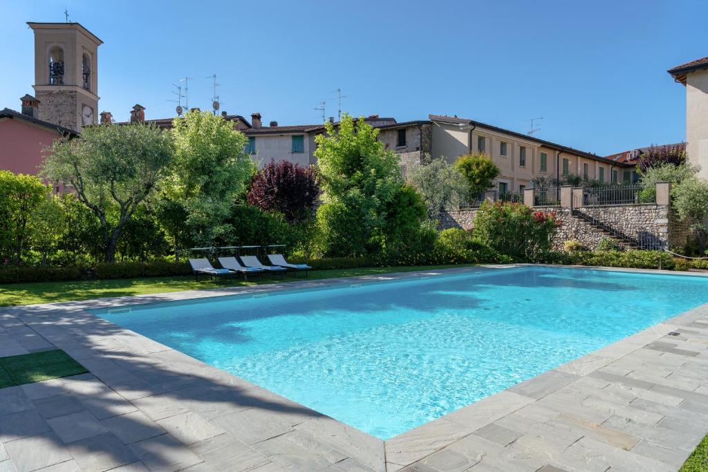 a large swimming pool in a yard with two chairs at Appartamenti Palazzo Scolari in Polpenazze del Garda