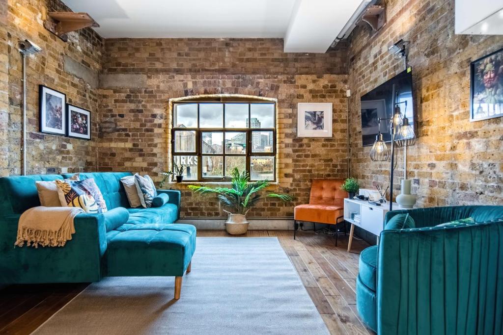 a living room with blue couches and a brick wall at Livestay-Fabulous Three Bed Warehouse Conversion Apartment in London