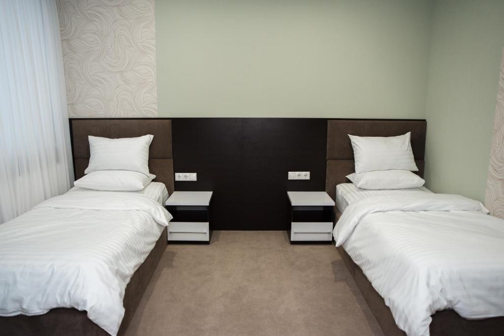 2 camas en una habitación con sábanas y almohadas blancas en Hotel VinoGrad en Haysyn