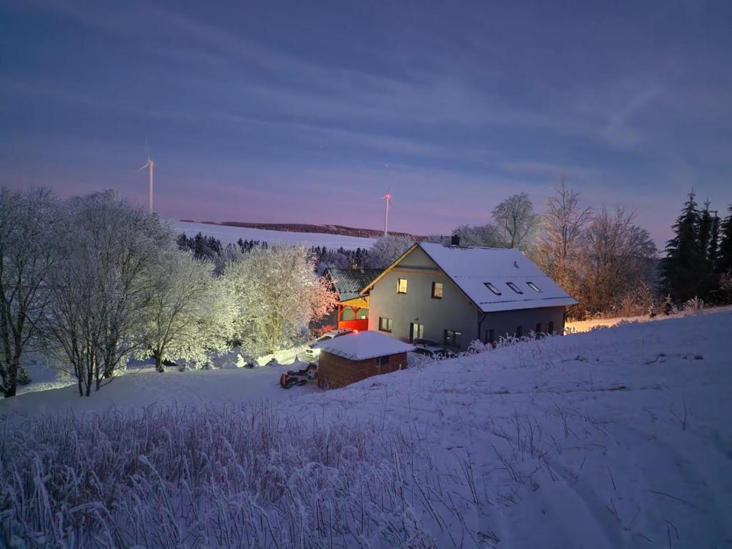 a house in a field with snow on the ground at Apartmány Čtyřlístek in Loučná pod Klínovcem