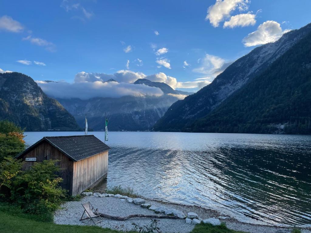 une cabine sur la rive d'un lac avec des montagnes dans l'établissement Untersee24 - Lake Hallstatt Apartment, à Bad Goisern