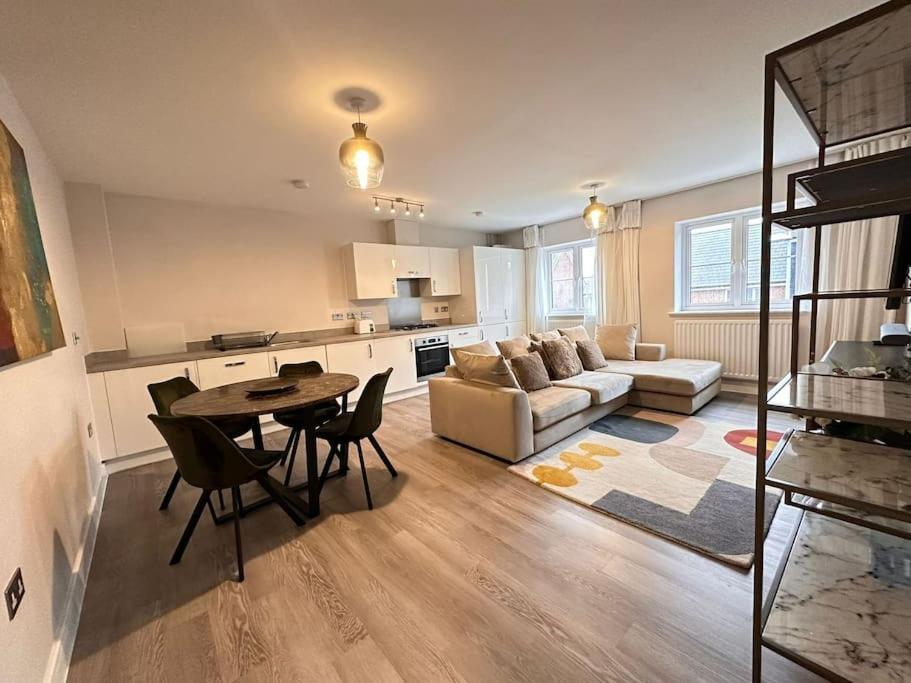 a kitchen and living room with a table and a couch at Hömli Close2City Apartment in Faygate