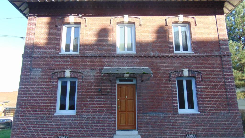 un edificio de ladrillo rojo con una puerta marrón en Les Pommerets, en Le Petit-Couronne
