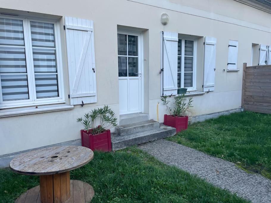 a table in front of a house with two potted plants at centre Pierrefonds superbe appartement + parking in Pierrefonds
