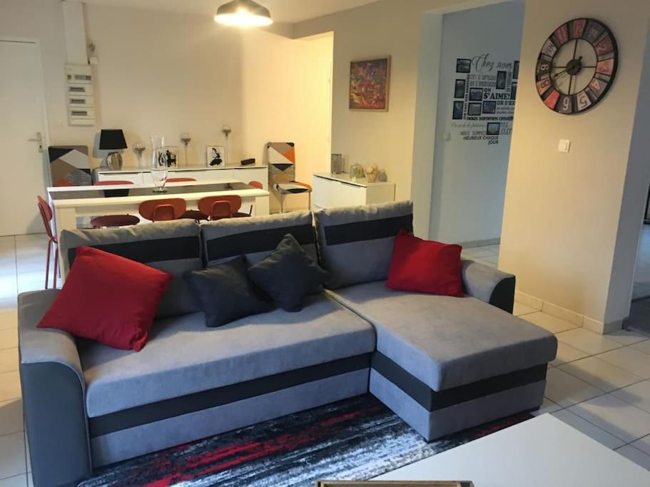 un sofá con almohadas rojas en la sala de estar. en centre Pierrefonds superbe appartement + parking, en Pierrefonds