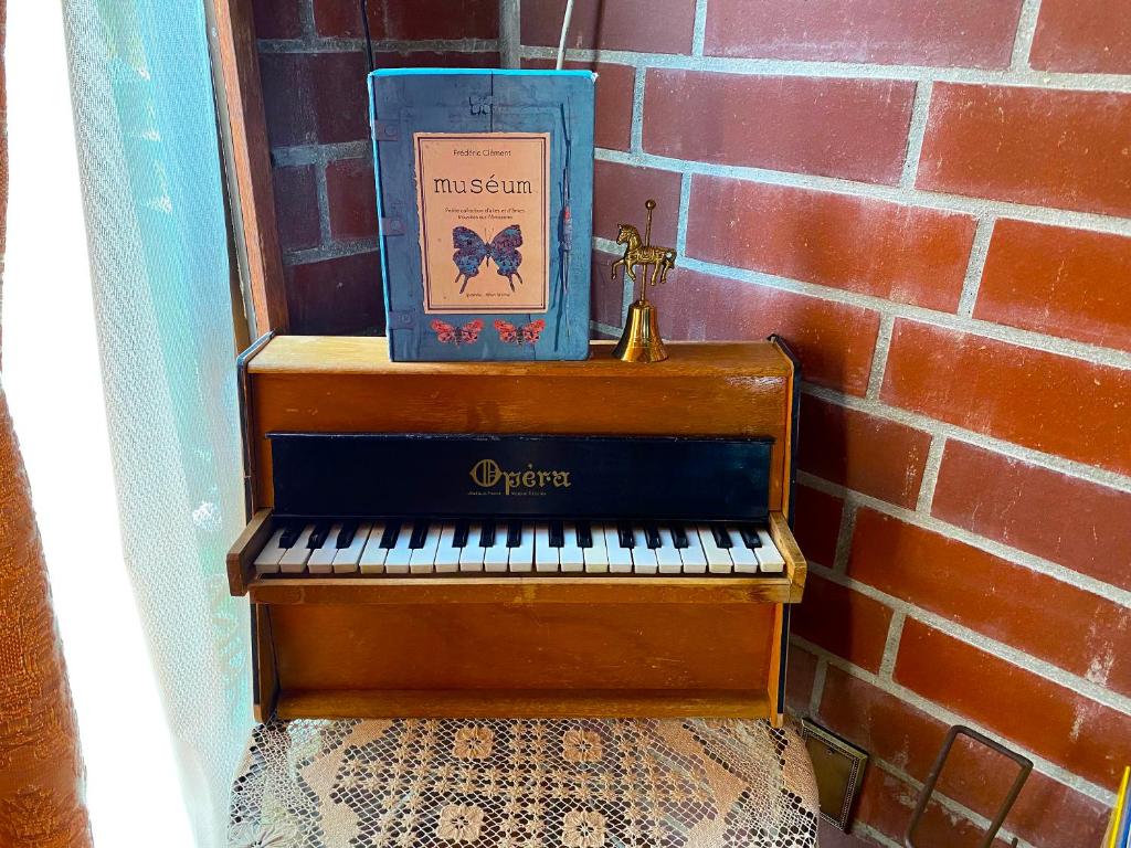 un libro sentado en la parte superior de un piano junto a una pared de ladrillo en 猫とピアノと星空のリゾートブティックコテージ - Starry Forest Cottage Okinawa -, en Onna