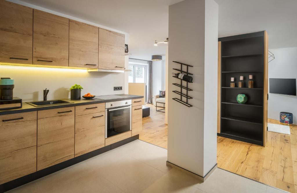 een keuken met houten kasten en een zwarte koelkast bij Auhof - Apartments Bad Gastein in Bad Gastein