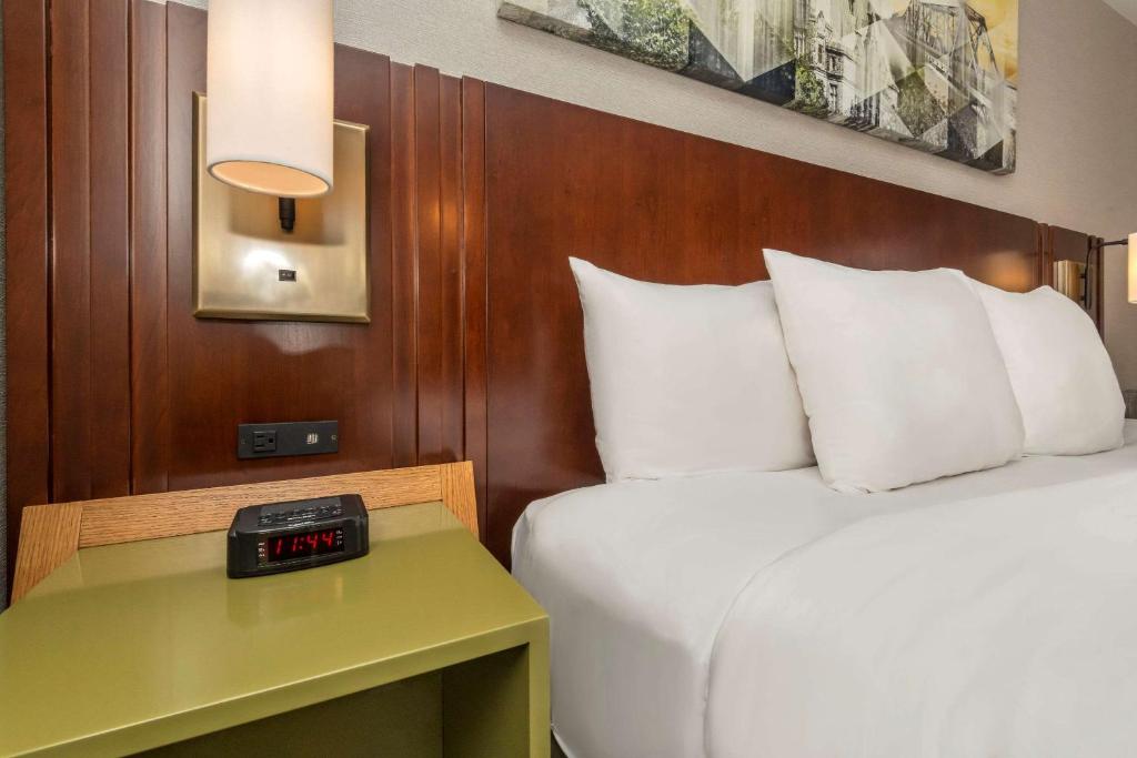 a hotel room with a bed and a clock on a table at Comfort Inn in Sault Ste. Marie