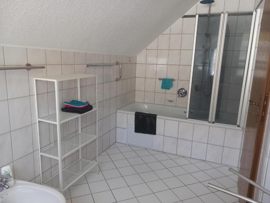 uma casa de banho em azulejos brancos com um chuveiro e um lavatório. em Zur alten Metzgerei em Alf
